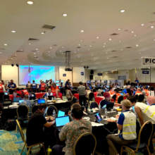 An exercise control room with dozens of people working at desks