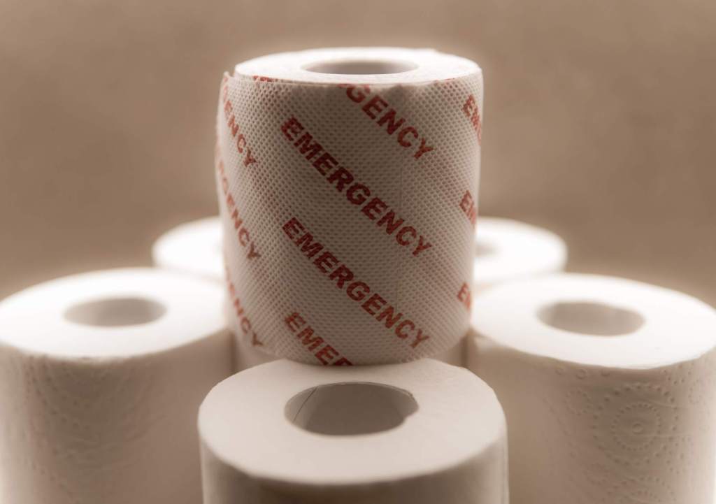 Pile of toilet rolls. Top most roll printed with emergency in red letters