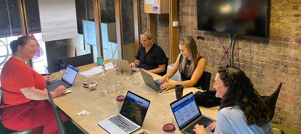 people sitting in office around a table working and looking happy