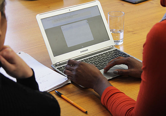 looking over the shoulder of a woman typing onto tablet