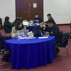 People working around a table with a blue table cloth on top 