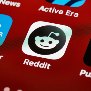 A screen grab of the Reddit logo on a phone with a red background